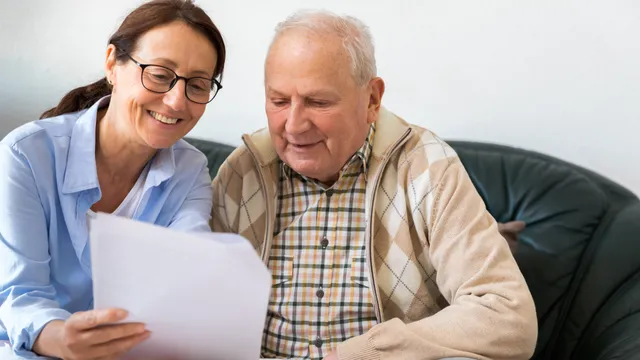 Adult daughter and elderly father reviewing special needs trust documents together in a supportive home environment in Florida.