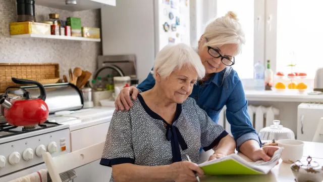 Adult daughter helping elderly parent prepare legal documents during crisis