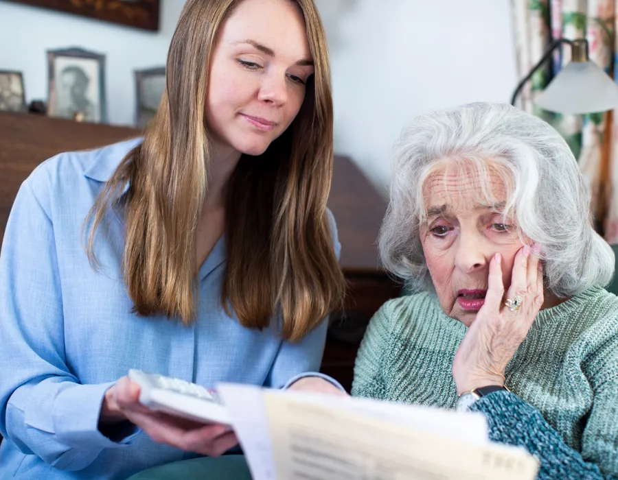 Concerned elderly woman reviewing paperwork with her adult daughter during a guardianship planning conversation at home in Florida.