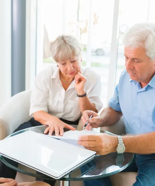 Elder law attorney meeting with senior couple to review Medicaid planning documents in a warm, professional office