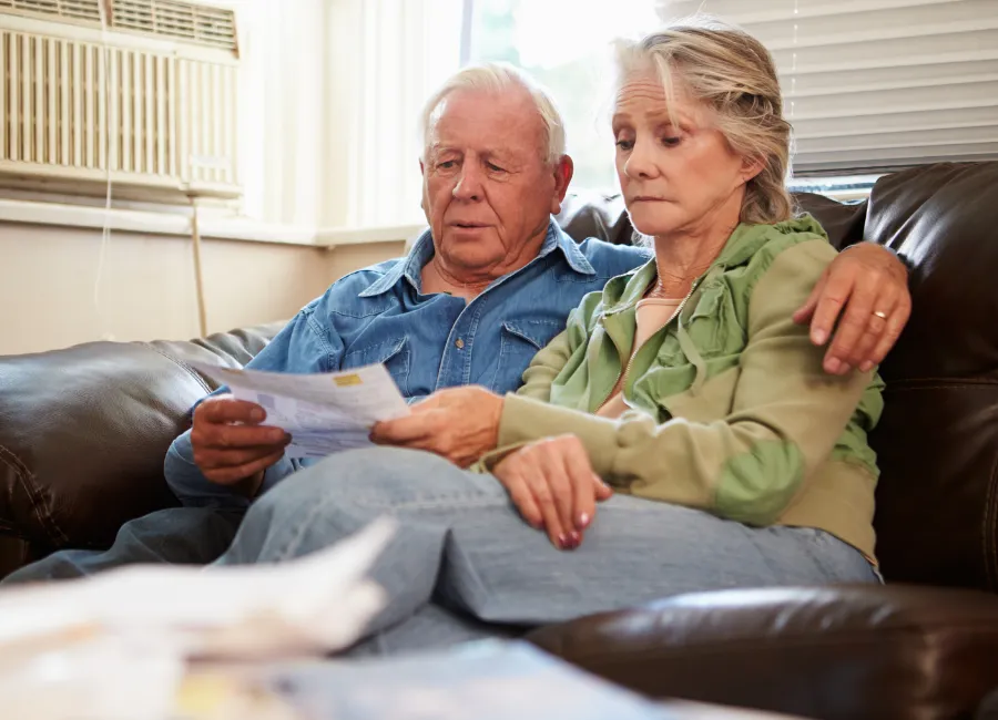 Elderly couple reviewing urgent paperwork together with visible concern during a legal or care-related crisis