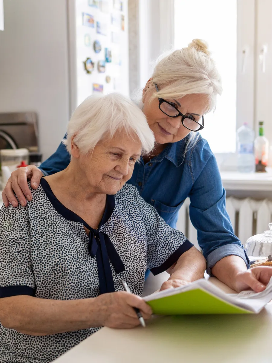 Elderly woman completing guardianship paperwork at home with support from her adult daughter in Florida.