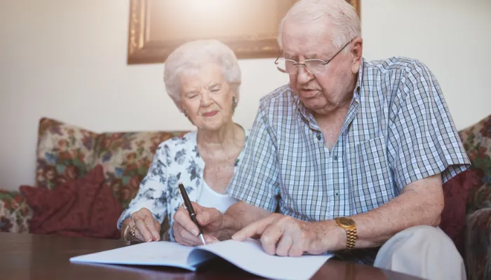 Middle aged couple handing completed paperwork looking reassured, after Amy handels their Medicaid eligibility requirements.