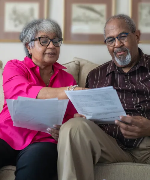 Senior couple reviewing healthcare documents together on the couch in a calm home setting