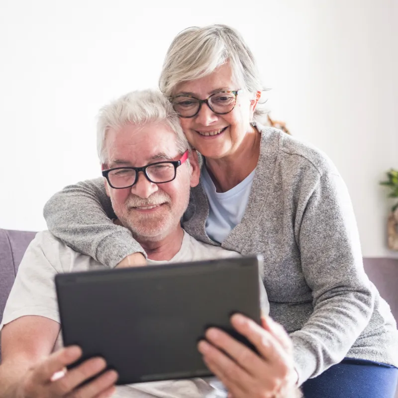 Senior couple smiling at home while reviewing their Lady Bird Deed documents on a tablet in Florida