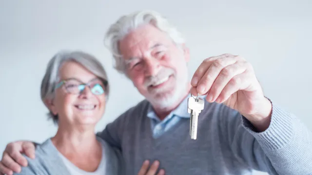 Smiling senior couple holding house keys after securing a Lady Bird Deed to retain full ownership and protect their home